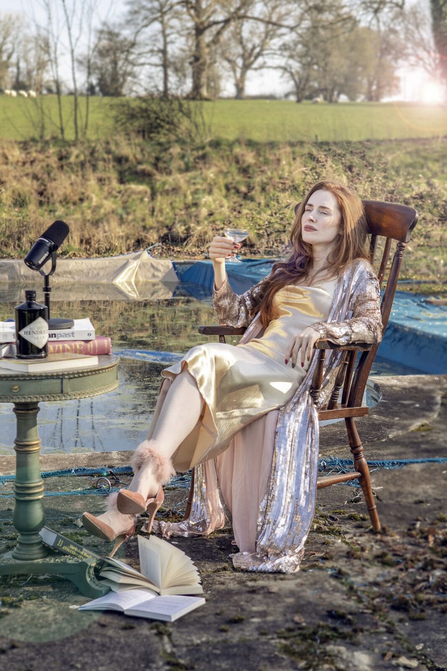 Rose at a desk in the middle of a pond, holding a drink